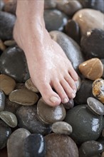 Close-up of woman's foot on pebbles.