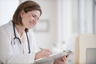 Female doctor writing on clipboard.