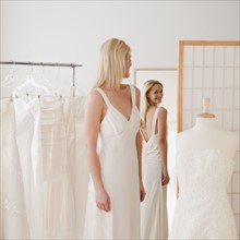 Young woman trying on wedding dress in bridal shop. Photographe : Jamie Grill
