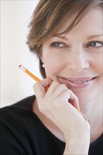Successful mature businesswoman holding pencil and smiling.