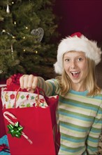 Teenage girl (13-15) wearing Santa hat holding Christmas gift. Photographe : Sarah M. Golonka