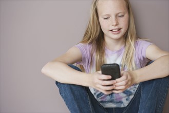 Girl (10-12) sitting and text messaging. Photographe : Sarah M. Golonka