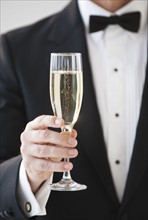 Champagne being held by a man in a tuxedo.