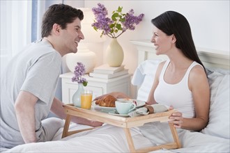 A man bringing a woman breakfast in bed.