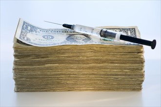 A syringe on a stack of banknotes