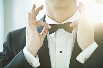 A man in a tuxedo fixing his bowtie