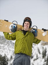 A snowboarder holdiing his snowboard