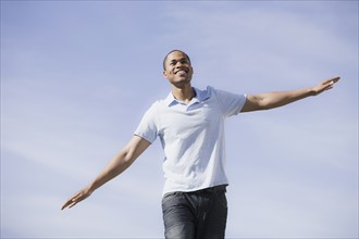 A man outdoors with arms out