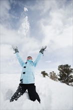 A woman throwing snow up in air