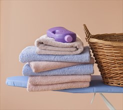 An ironing board with towels and detergent.