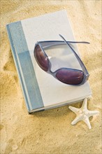 A book with sunglasses on sand