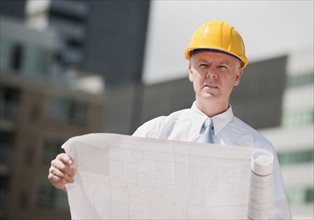 An architect holding plans outdoors.