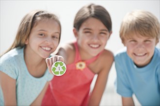 Three children with a recycling button.