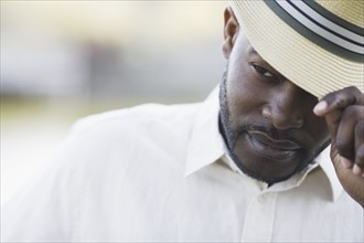 A man outdoors fixing his hat