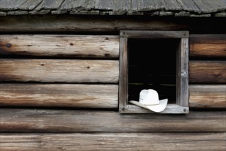 A cowboy hat in the window of a cabin