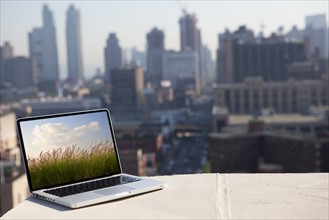 A computer in the city with an image of a countryside