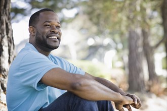 A man sitting outdoors by a tree