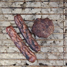 Burnt wieners and a burger on a barbeque