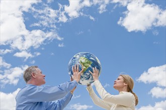 Two people holding up a globe.