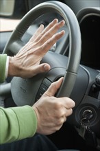 A hand honking a horn in a car.