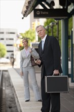 Two business people at a train station.
