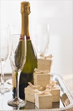 Champagne on a tray with small gift boxes.
