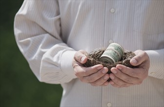Hands holding a nest with money in it.