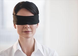 Businesswoman wearing blindfold.