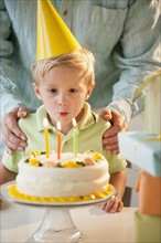 Young child blowing out birthday candles.