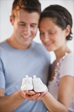Couple holding baby shoes.