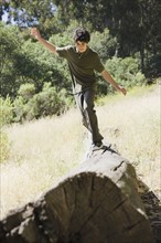 Young male balancing on log