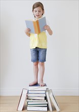 Child reading while standing on books