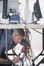 Man under table working on networked computers.
