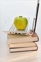 Apple on laptop and books.
