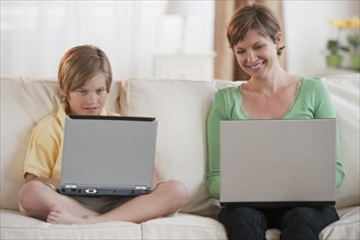 Mother and son on laptops.