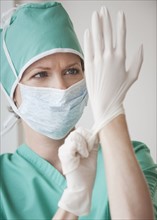 Female doctor putting on gloves.