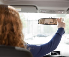 Woman adjusting driving mirror
