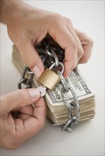 Hands placing lock around money.