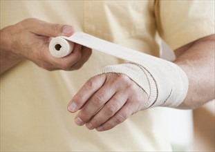 Man wrapping hand in tensor bandage.