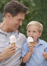 Father and child eating ice cream cones.