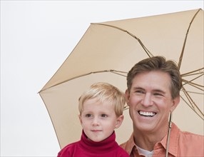 Father and child under umbrella.