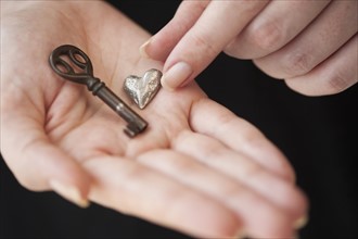 Hands holding heart and key.
