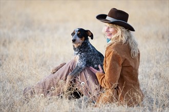 Woman and dog sitting in field.