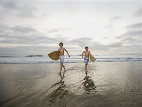 Boys running with surfboards