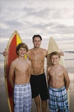 Father and sons standing with surfboards