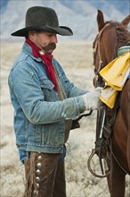 Man adjusting saddle on horse.