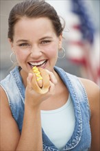 Woman eating hotdog.