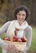 Woman holding basket of apples.