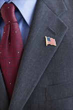 Business suit with pin of American flag on lapel.