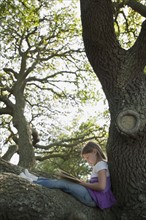 Girl reading book in tree